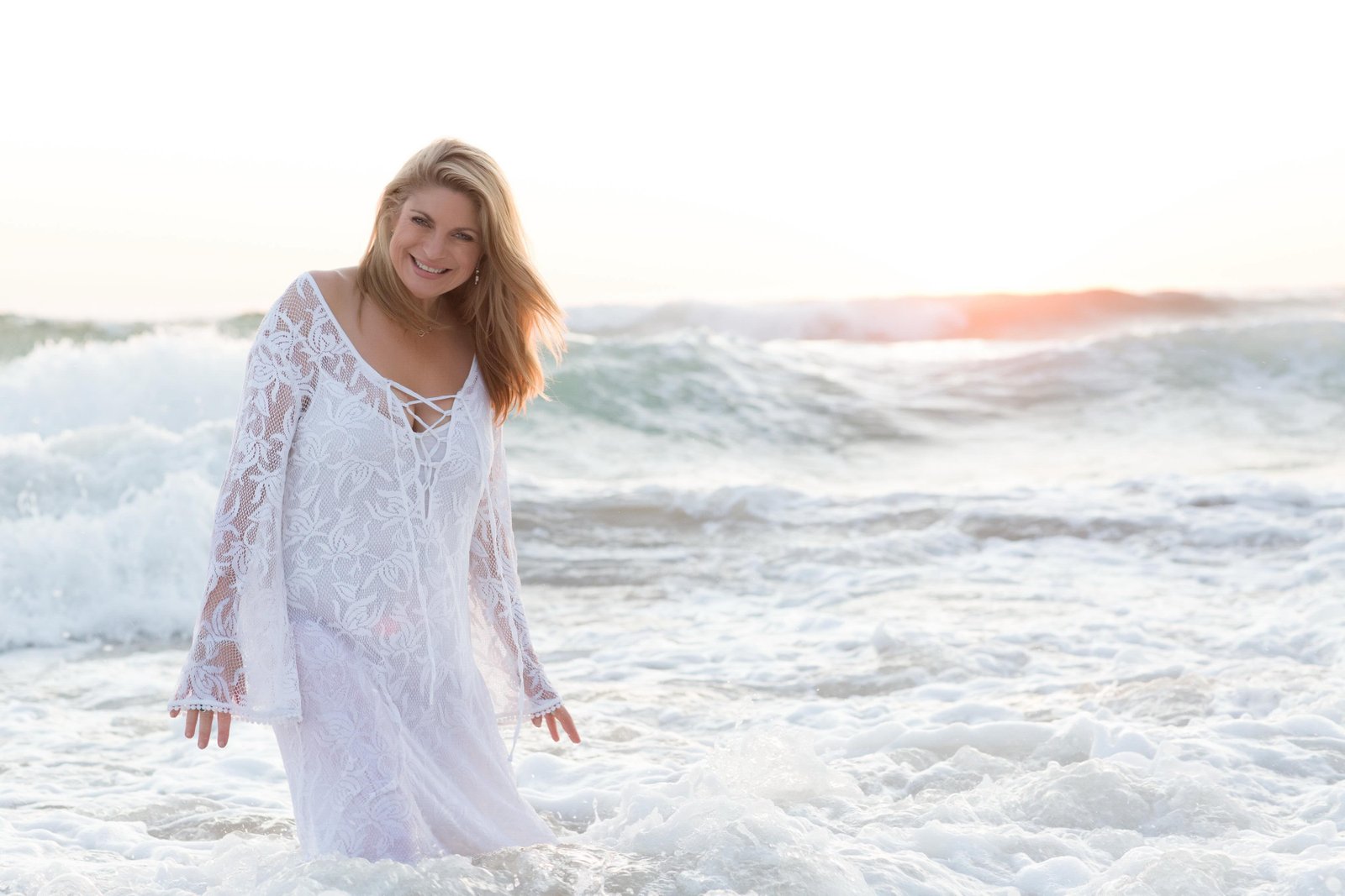 Maria Therase laughing in the ocean at sunrise, white lace dress